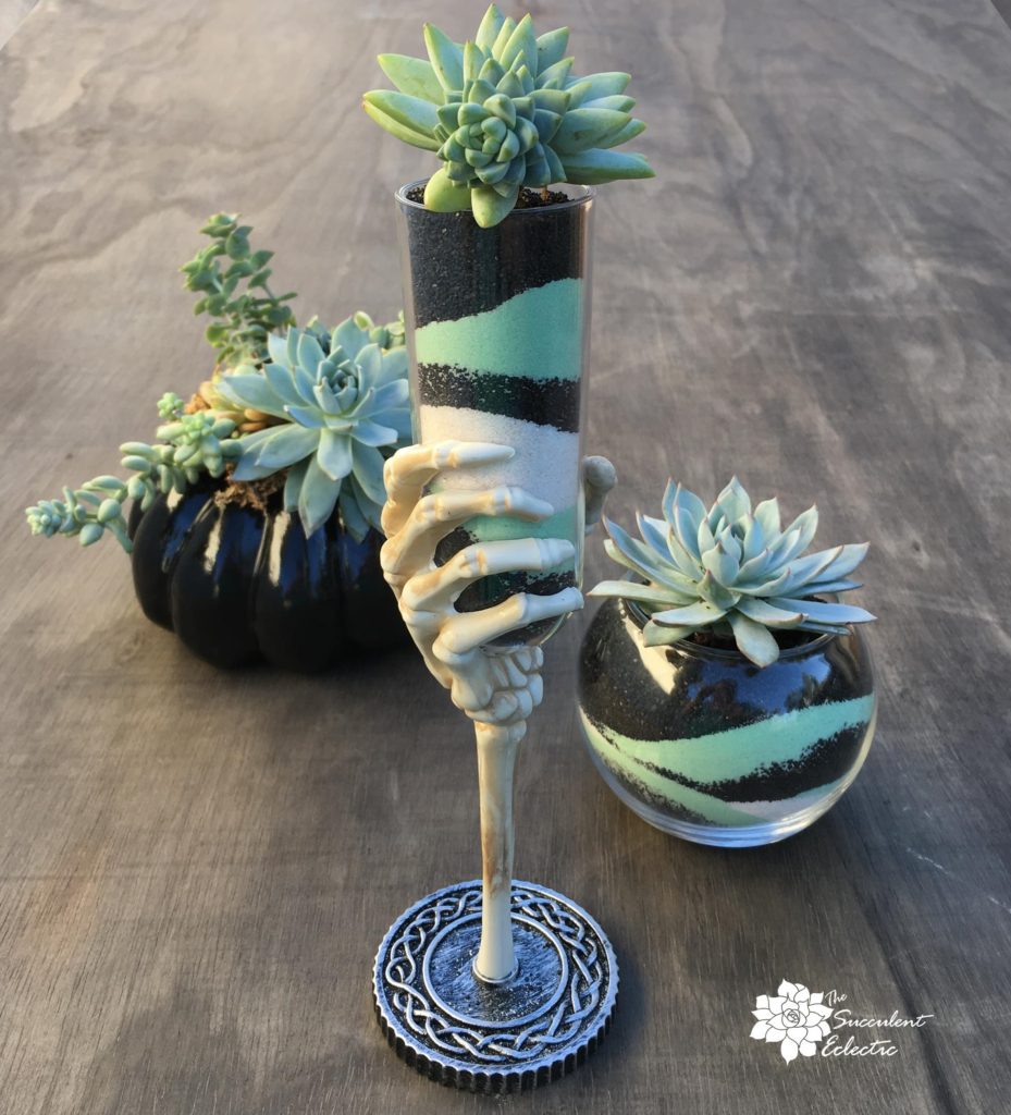 succulent sand art in skeletal hand chalice and glass bowl